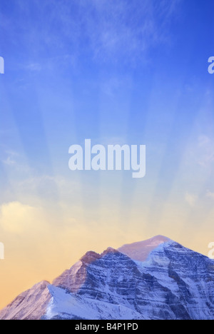 Sun rising behind a big snowy mountain background with sun rays Stock Photo