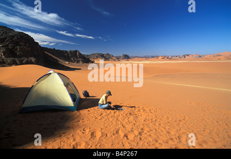 Algeria near Djanet Sanddunes Tourist sits in front of tent. Camping in Sahara Desert. Stock Photo