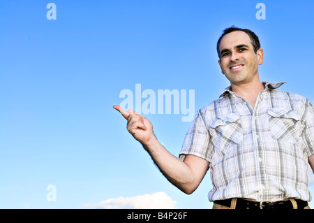 Happy middle aged man gesturing on blue sky background Stock Photo