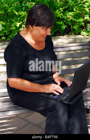 Mature woman typing on portable computer outdoor Stock Photo