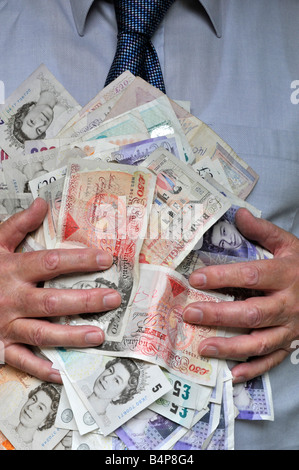 Wad of cash made up of sterling UK pound currency bank notes with hands holding money to mans chest & held by grasping fingers concept image England Stock Photo