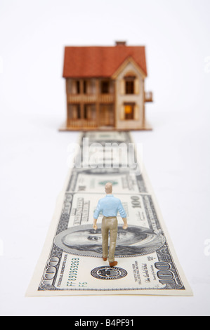 Male figurine walking on pathway towards model house Stock Photo