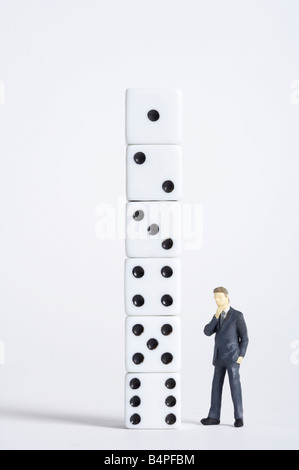 Male figurine standing in front of dice pillar Stock Photo