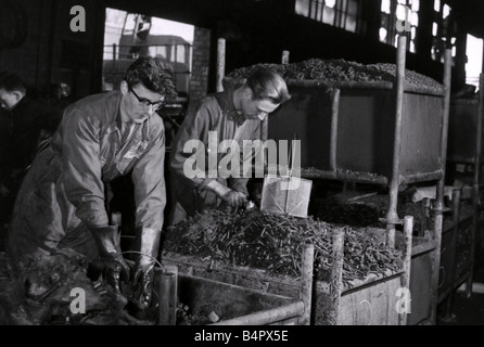 Only a few hours after Coventry firemen had doused the last of the flames workers in gum boots were toiling among the wreckage to clear the vital assembly lines at the Jaguar car factory Though fire blackened and rust these bolts and washers and many other spare parts can be salvaged and used again 1957 Stock Photo