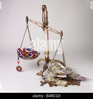 set of scales, Olympic medals on one side, various currency coins and notes on the other Stock Photo