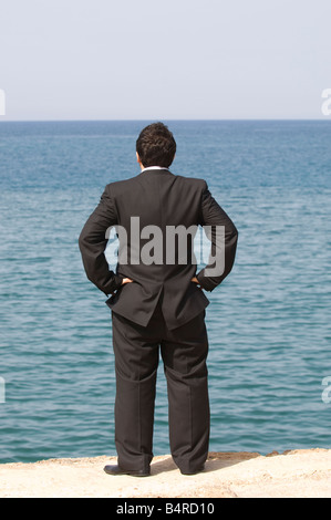 Rear view of a business man in suit standing at the sea Stock Photo