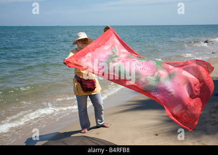 Thai woman trader displaying beach tourist sarong at Paknampran Pranburi Khiri Khan, Thailand Stock Photo