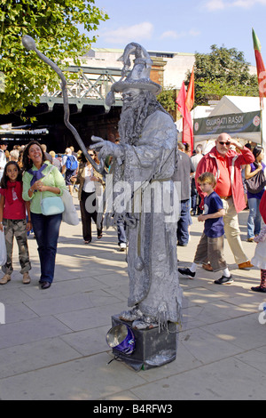 Man dressed in silver as a living statue of Merlin seen on the Thames Embankment during the London Arts Festival Stock Photo