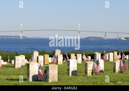 Historic cemetery with American flags in Fort Adams State Park Newport Rhode Island with Pell Bridge and ocean in Background Stock Photo