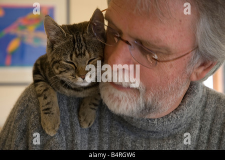 Bearded middle aged man wearing glasses with cat on his shoulder Stock Photo