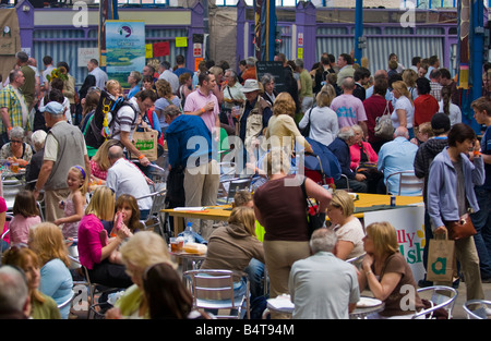 Crowds of people wander sit and browse stalls ain Market Hall at Abergavenny Food Festival Stock Photo