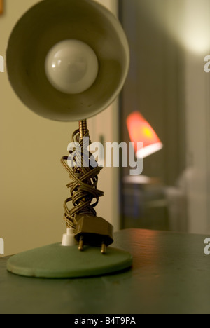 detail of retro lamp on table with wire coiled round stem and light red lamp reflected in background Stock Photo