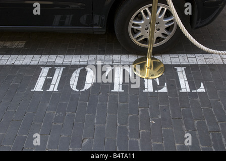 looking down at the word 'hotel' stencilled on the road next to parked luxury car cordoned off in front of classy hotel Stock Photo