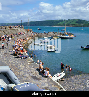 Holidaymakers sitting on the stone pier with a view across the harbor and bay in New Quay West Wales UK   KATHY DEWITT Stock Photo