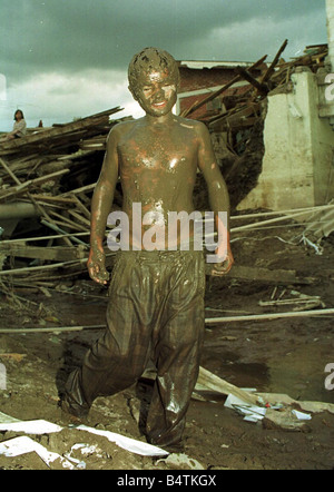 Honduras Hurricane Aftermath November 1998 Melvin boy aged 14 years old caked in mud scavenges in the Market Area of third street from River Choluteca in Capital City of Tegucigalpa in Honduras looking for clothing which his family can wash and sell or exchange for food following flooding caused by heavy rains from Hurricane Mitch Stock Photo