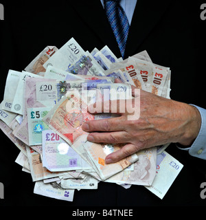 Man in dark office business suit hand on close up stack of money bank notes uk cash currency concept for bankers fat cats greed Men in Suits Lifestyle Stock Photo