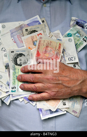 Old man holding on to sterling UK pound cash currency bank notes with hand grasping money to his chest & held tight by veined wrist & fingers England Stock Photo