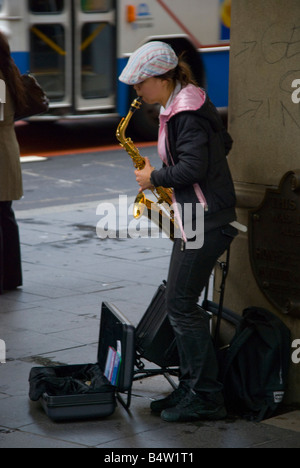 A busking female saxophone player in inner city CBD Sydney Australia Stock Photo