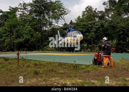 Helicopter landing at remote jungle onshore oil site in rainforest with oil workers, Gabon, Western Africa Stock Photo