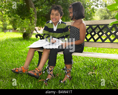 Asian kids reading a book in a park Stock Photo