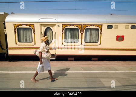 A sadhu (holy man) walks past a carriage from the 'Palace on Wheels' train, Bharatpur station, Rajasthan, India Stock Photo