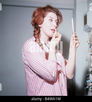 Heller Toren model actress 1964 puting on lipstick holding hand mirror pink striped shirt Stock Photo