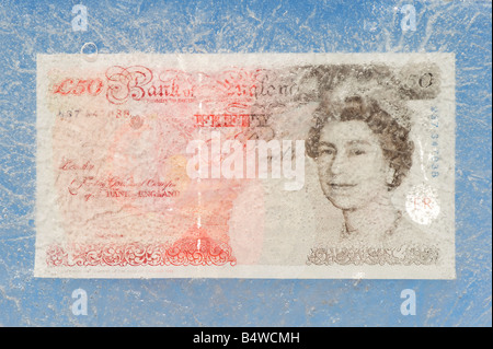 Fifty pound note frozen in ice Stock Photo