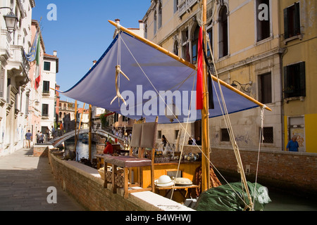 Antiques and Flea market bits for sale on a boat in a small canal in Venice Stock Photo