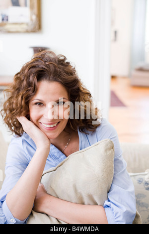 Woman hugging pillow sitting on a couch Stock Photo
