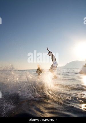 Couple jump off back of sailboat Stock Photo