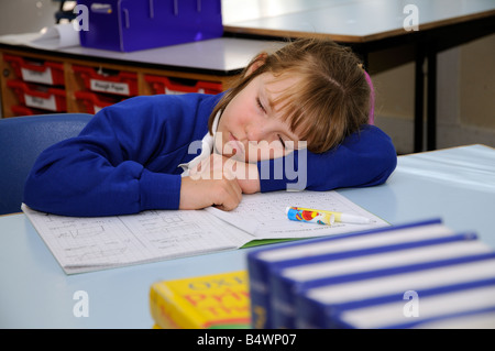 Schoolgirl asleep on her desk Pupil sleeping in school classroom Stock Photo