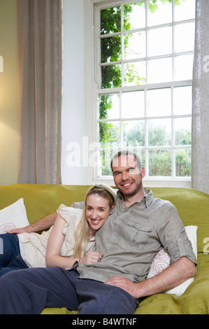 Couple sitting on couch, smiling Stock Photo
