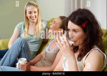 Three young women seated on couch Stock Photo