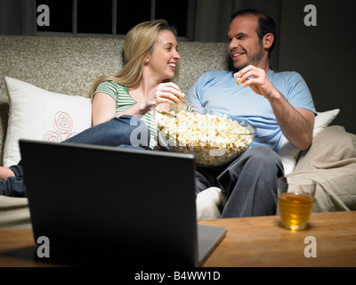 Young couple sharing popcorn on couch Stock Photo