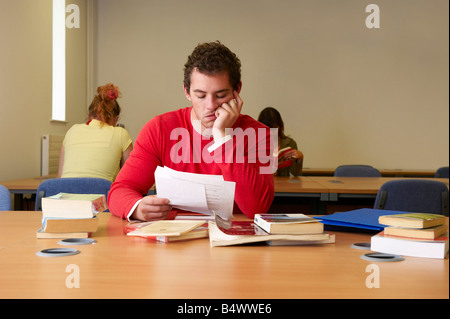 Bored young man seated at desk studying
