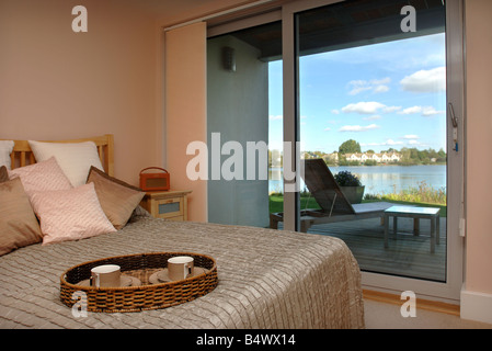 A BEDROOM WITH A BALCONY IN A WATERSIDE APPARTMENT AT THE LOWER MILL ESTATE NEAR CIRENCESTER GLOUCESTERSHIRE UK Stock Photo