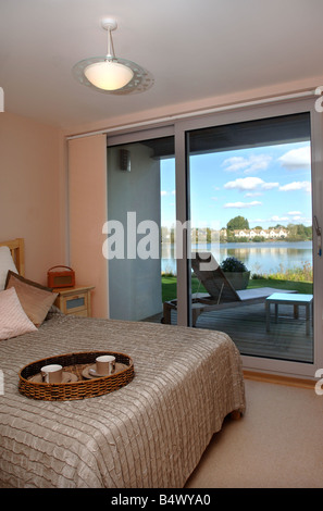 A BEDROOM WITH A BALCONY IN A WATERSIDE APPARTMENT AT THE LOWER MILL ESTATE NEAR CIRENCESTER GLOUCESTERSHIRE UK Stock Photo