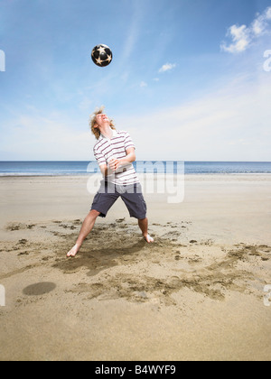 Young man with football on beach Stock Photo