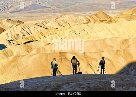 Three photographers catching the perfect shot of sunrise at Zabriskie Point in Death Valley National Park in California. Stock Photo