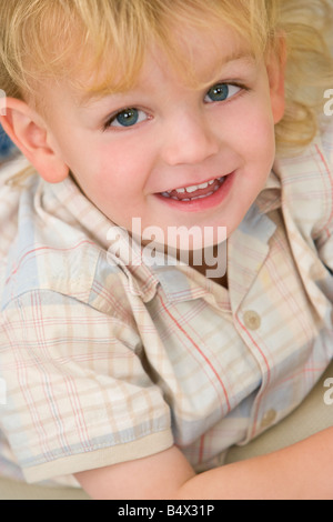 A young blond boy laying down and giving a cheeky grin Stock Photo