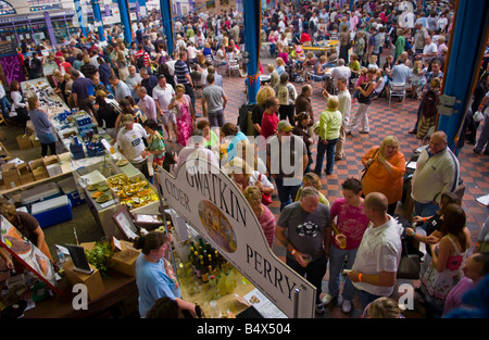 Crowds of people wander sit and browse stalls ain Market Hall at Abergavenny Food Festival Stock Photo