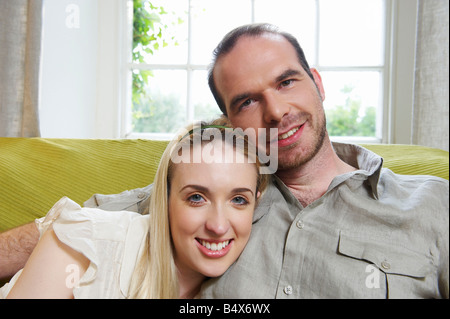 Couple sitting on couch, smiling Stock Photo