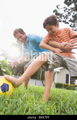 Father and son playing soccer in backyard Stock Photo