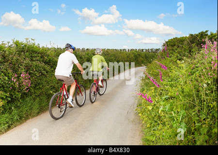 Senior couple cycling up country lane Stock Photo