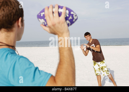 Friend playing football on beach Stock Photo