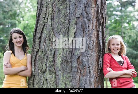 Girls leaning against large tree Stock Photo