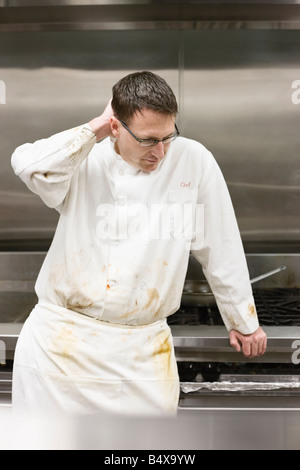 Tired chef leaning against stove Stock Photo