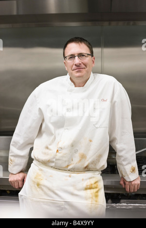 Dirty chef leaning against stove Stock Photo