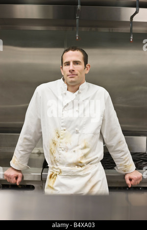 Dirty chef leaning against stove Stock Photo