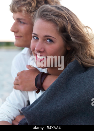 Young couple wrapped in blankets on beach Stock Photo